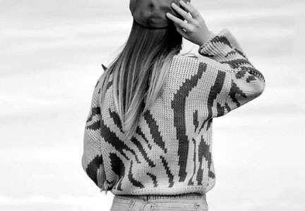 A fashion forward woman confidently wears a black-and-white knitwear garment.